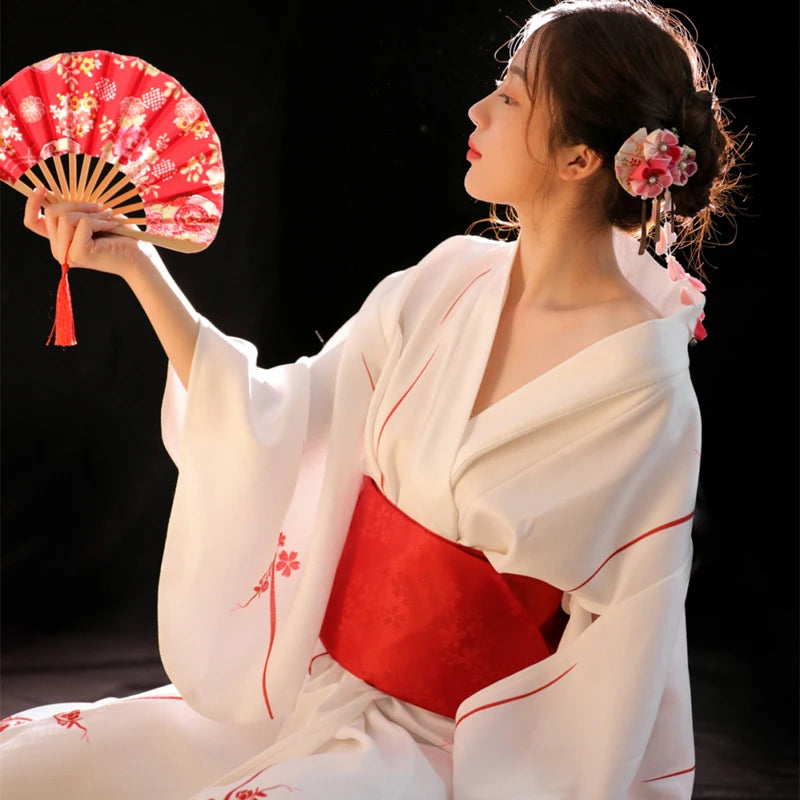 Kimono blanc avec obi rouge, vêtement traditionnel japonais porté lors de cérémonies.