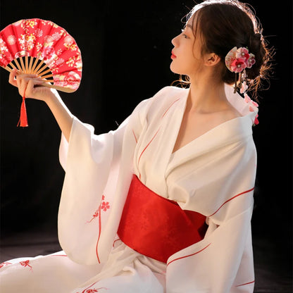 Kimono blanc avec obi rouge, vêtement traditionnel japonais porté lors de cérémonies.